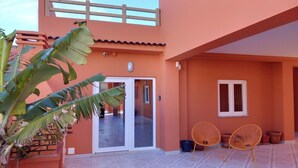 A building with a tiled patio, a sliding glass door, and two wicker chairs. - Guesthouse Beach Break (Peniche)