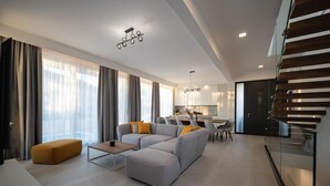 Un salon moderne avec un canapé d’angle, une table basse et un coin repas avec des chaises.
