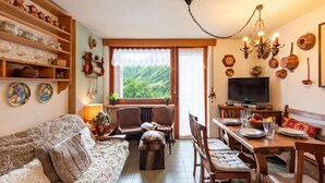 Un salon confortable avec un canapé, des fauteuils, une table à manger et un téléviseur.