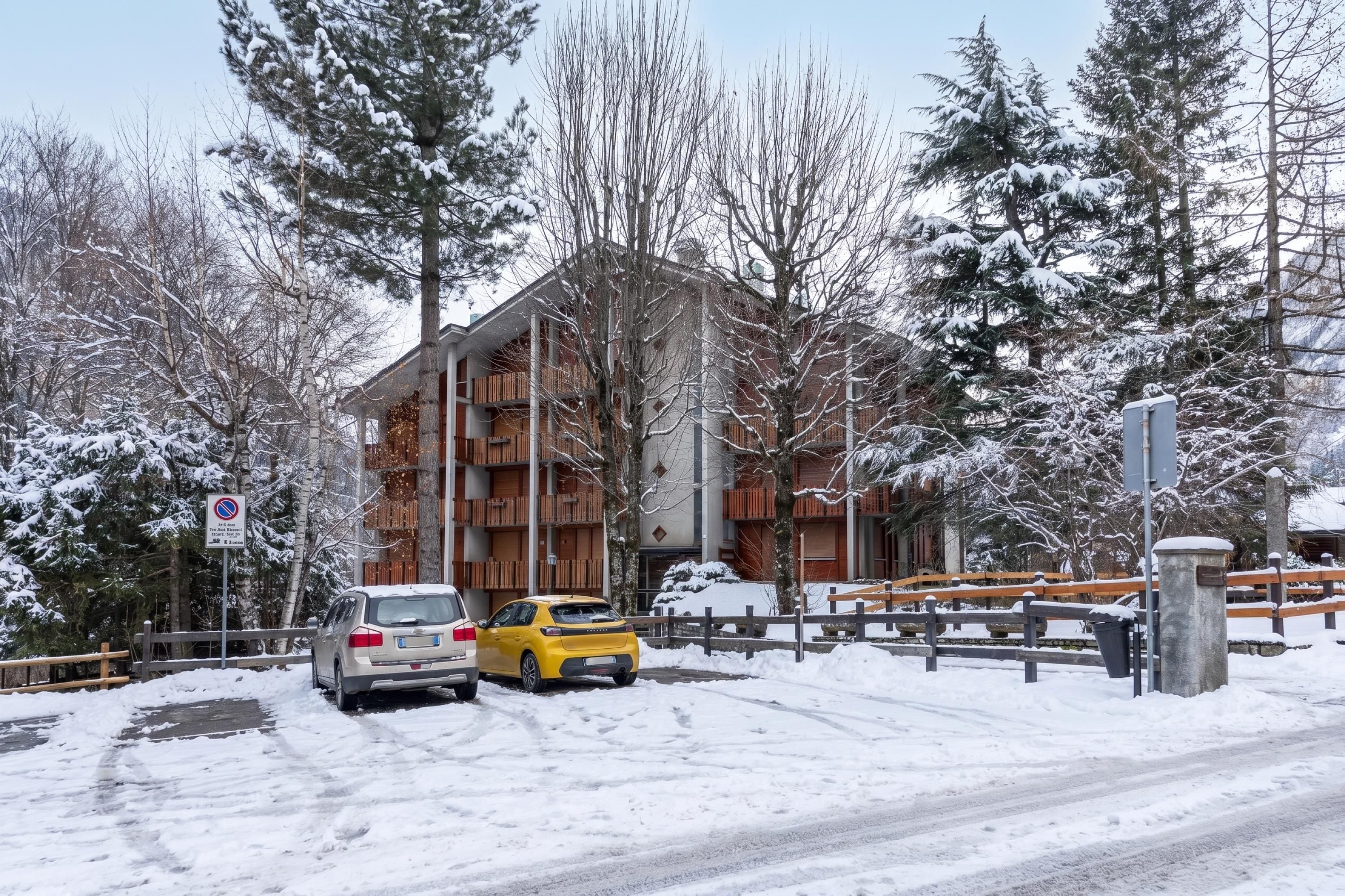A building with multiple balconies, a snow-covered landscape, and a no parking sign.