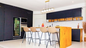 A modern kitchen with a central island, bar stools, and a built-in oven.