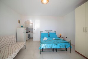 Une chambre comprenant un lit, un canapé, une armoire et un coin cuisine.