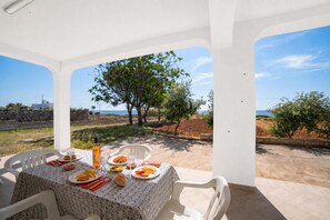 Une table dressée pour le dîner, avec vue sur la mer et les arbres.