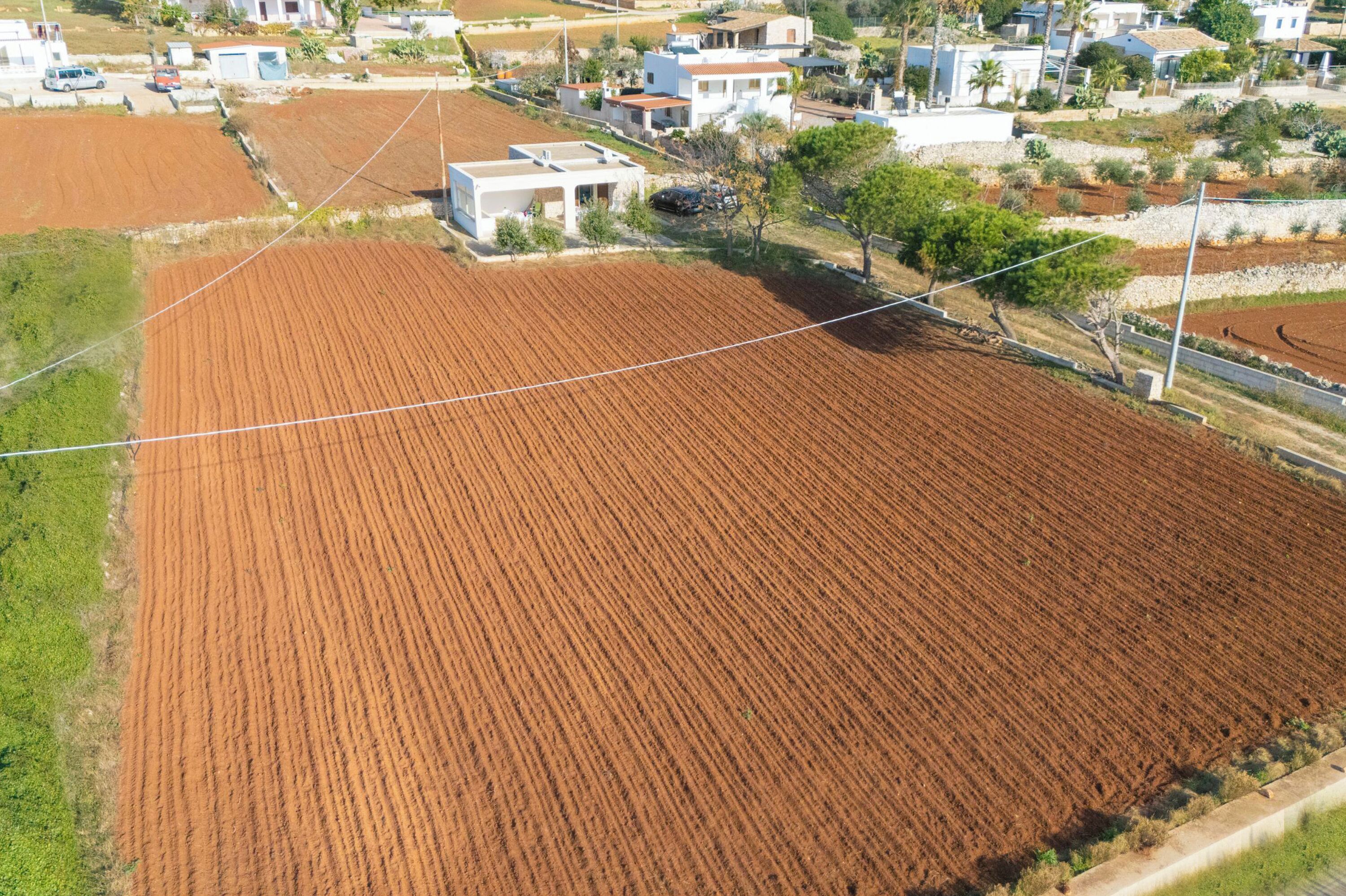 An aerial view of a residential area with a large, rectangular field, houses, and a small building.