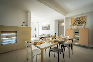 A dining area with a glass table, chairs, and a buffet cabinet.