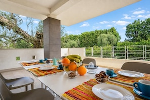 An outdoor dining area with a table set for breakfast, featuring fruits, pastries, and a view of the surrounding greenery. - Villa Torricella Pool and Sunny Garden (Leverano)