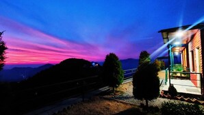 A building with a porch and a view of the mountains. - Deodar Inn resort (Kalsi)