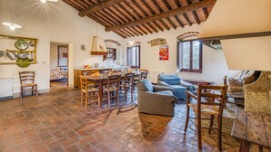 A spacious living area with a wooden dining table, several chairs, a sofa, and a piano. - Family Tuscany Villa with private pool (Civitella in Val di Chiana)