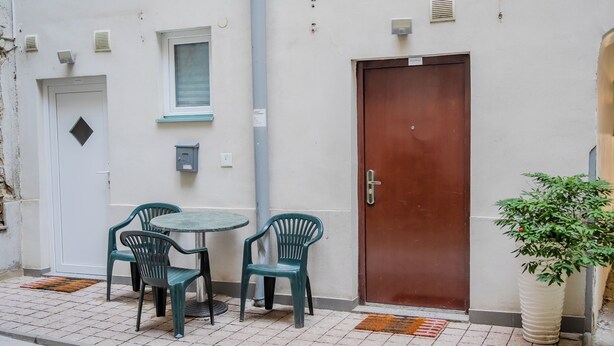A small outdoor seating area with a table and four chairs, a brown door, and a potted plant. - Red Vibe Studio Central 2 (Zagreb)