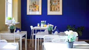 Un coin repas avec des meubles blancs, des murs bleus et deux tableaux encadrés.