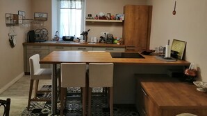 Una cocina compacta con encimera de madera, un lavamanos y un comedor con sillas.