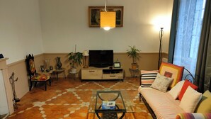 Una sala de estar con sofá, mesa de centro, televisor y plantas decorativas.