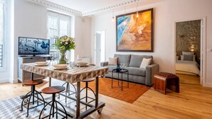 A modern living room with a dining area, a grey sofa, a coffee table, and a painting on the wall. - #République#Paris2#Chatelêt#2bedrooms (Paris)
