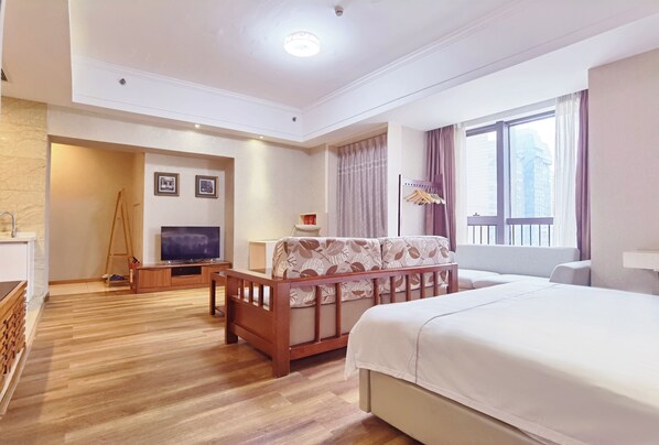 Habitación de hotel con una cama grande, un sofá de madera, un televisor y un escritorio.