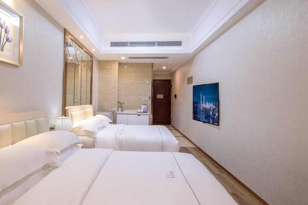 Habitación de hotel con dos camas, un baño, un cuadro de un paisaje urbano y una obra de arte enmarcada en la pared.