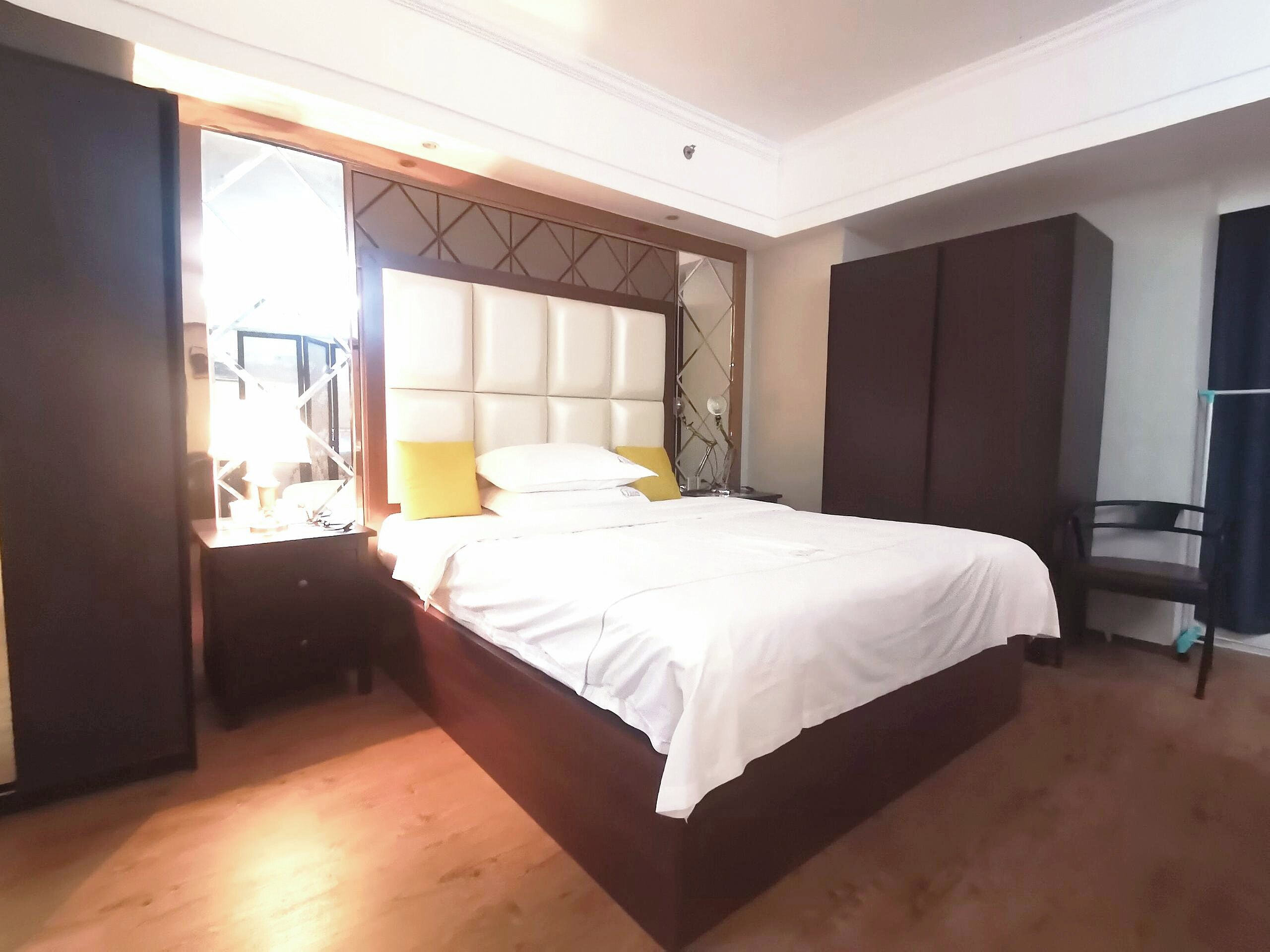 A bedroom with a large bed, a wardrobe, and a desk with a chair.
