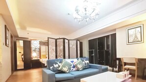 Una sala de estar moderna con un sofá azul, una mesa de centro blanca y una lámpara de techo decorativa.