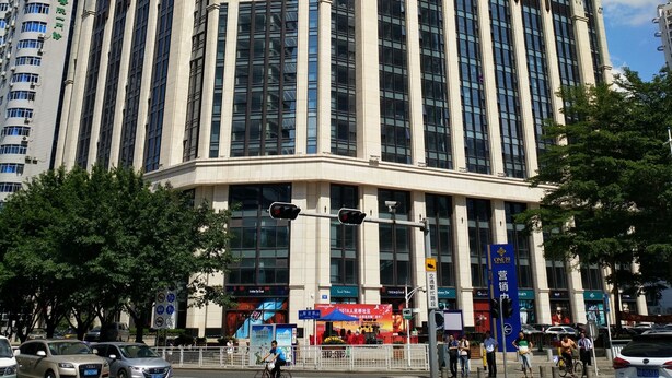 Un edificio alto y moderno con una fachada de ventanas en forma de cuadrícula y una entrada destacada.