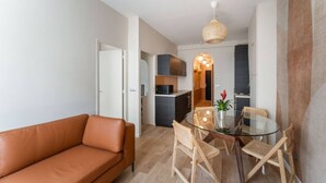 A modern living room with a leather sofa, a glass dining table with chairs, and a kitchen in the background. - Charming home in heart of PARIS!Opera/Eurostar 4pers (Paris)