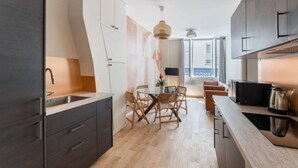 A modern kitchen with dark cabinets, a wooden dining table, and a coffee machine. - Charming home in heart of PARIS!Opera/Eurostar 4pers (Paris)