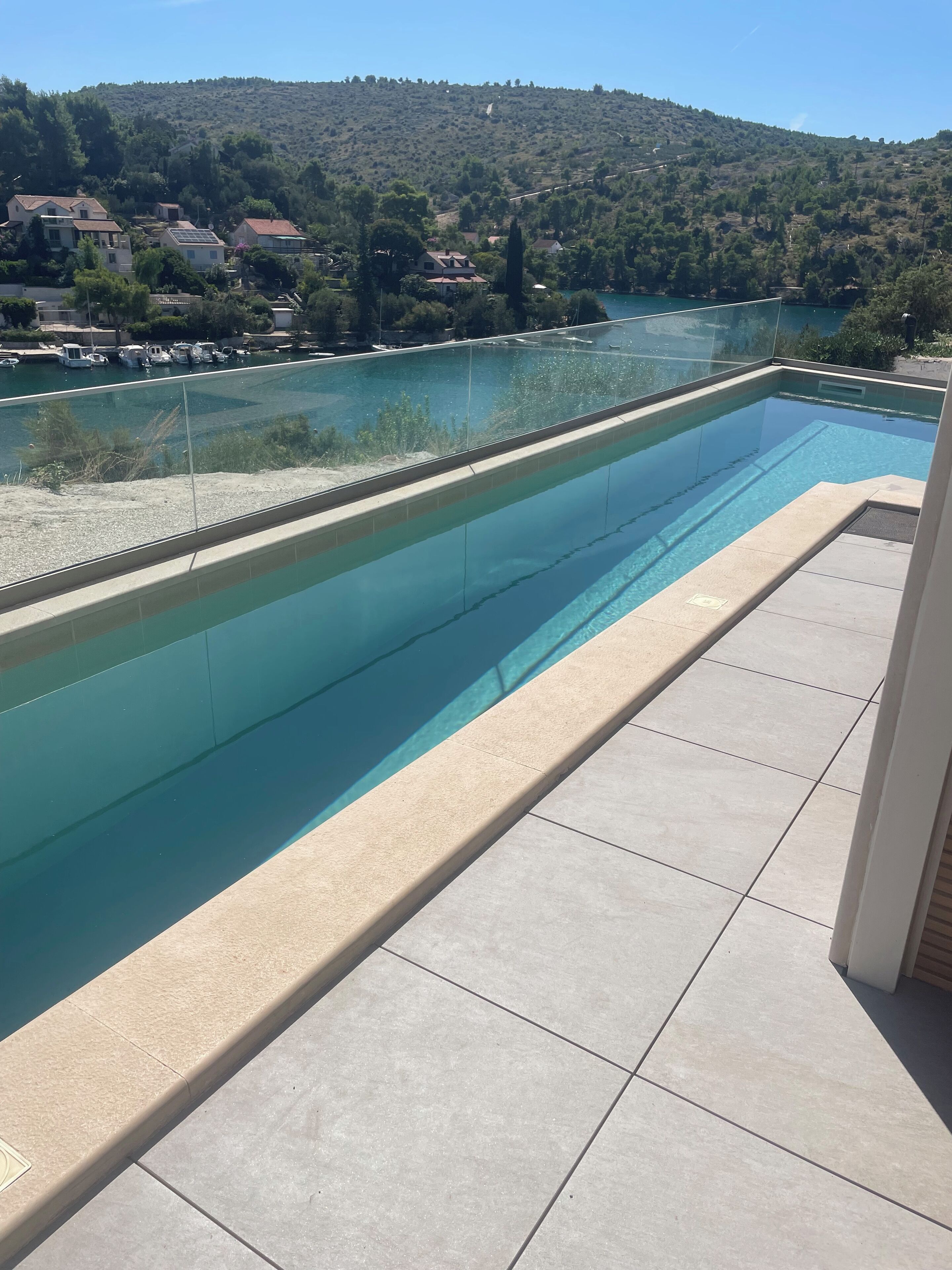 A swimming pool with a clear view of a lake and hills in the background.