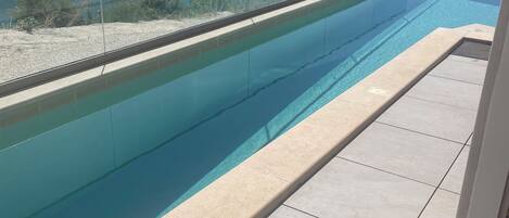 A swimming pool with a clear view of a lake and hills in the background.