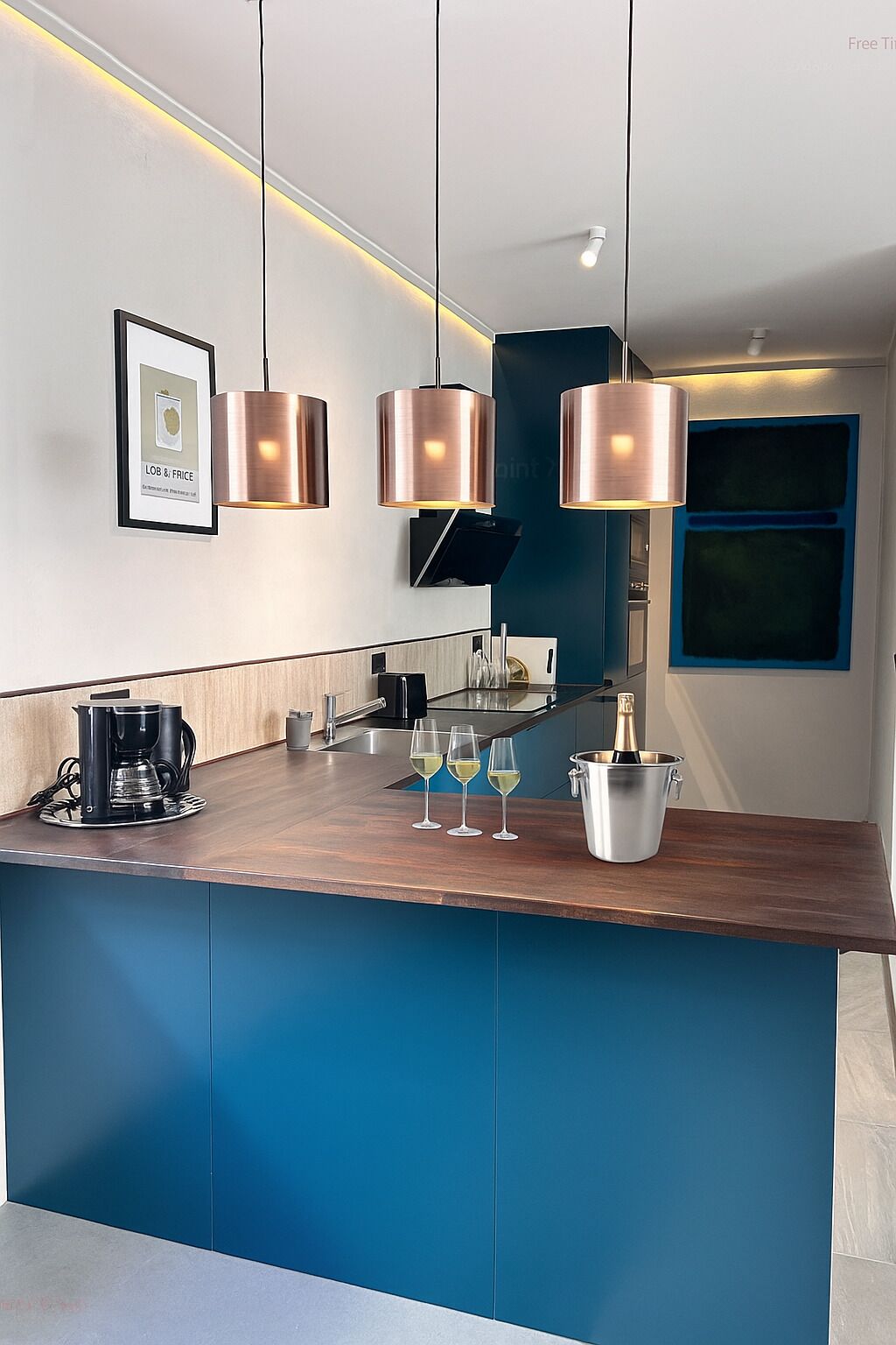 Una cocina moderna con encimera de madera, cafetera, copas de vino y una botella de champán.