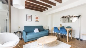 A modern living room with a blue sofa, a round coffee table, and a dining area with blue chairs. - New Duplex 6Pers#Paris Expo#Porte de Versailles (Paris)