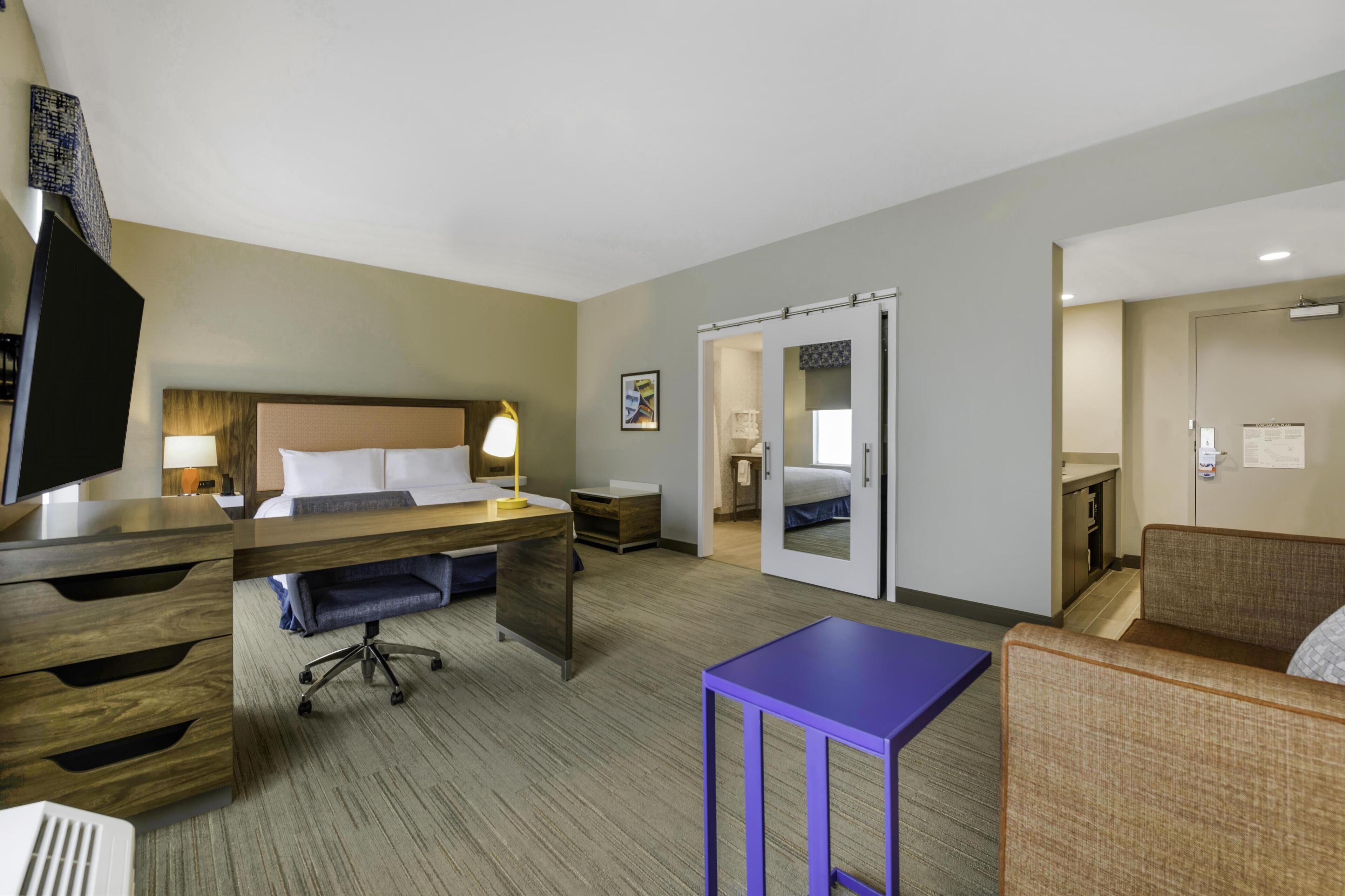 Une chambre d’hôtel avec un lit, un bureau, une chaise et une petite table.