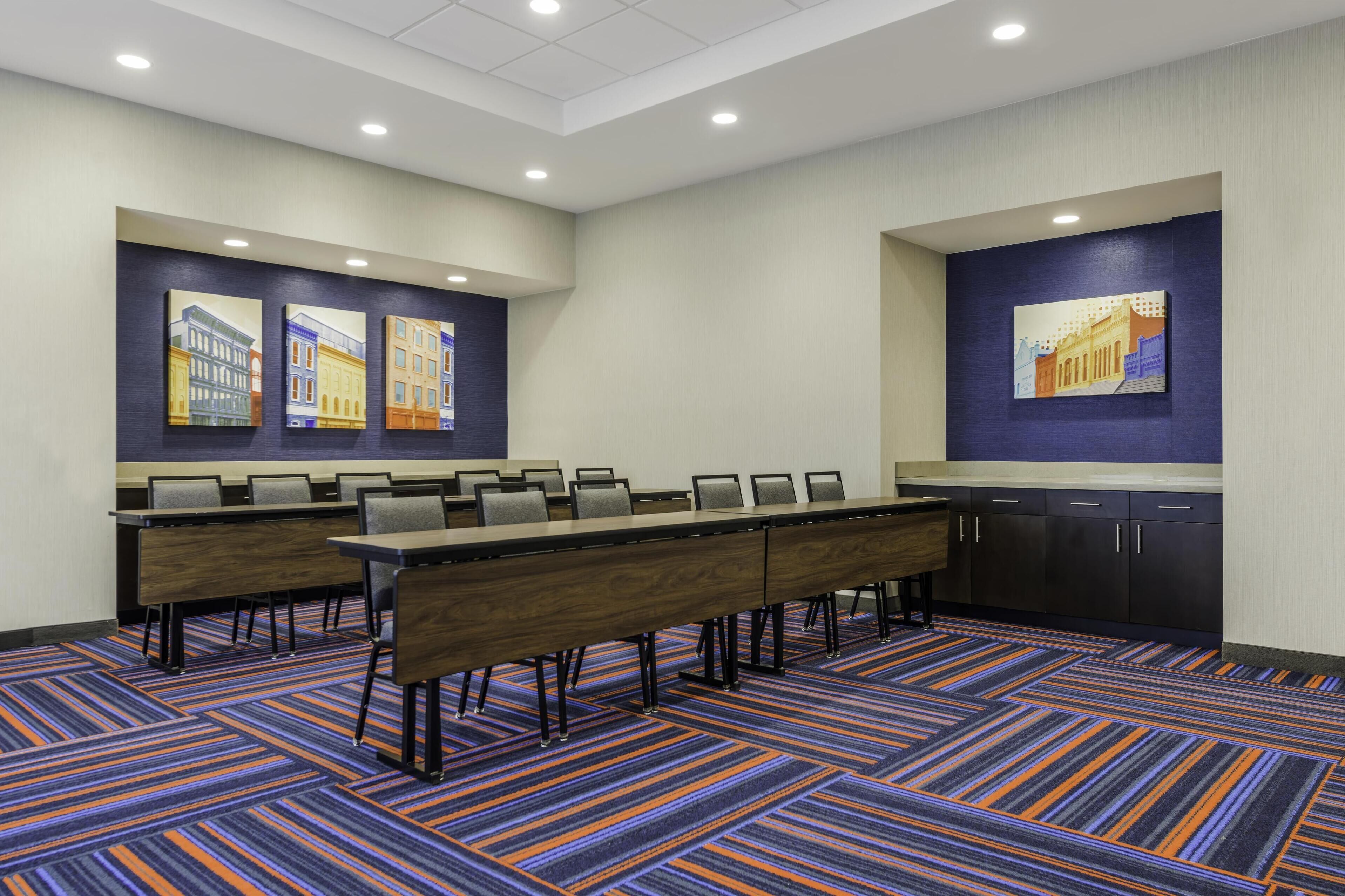 A conference room with a long table, chairs, and artwork on the walls.