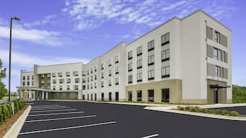 A modern hotel with a large parking lot and a covered entrance.