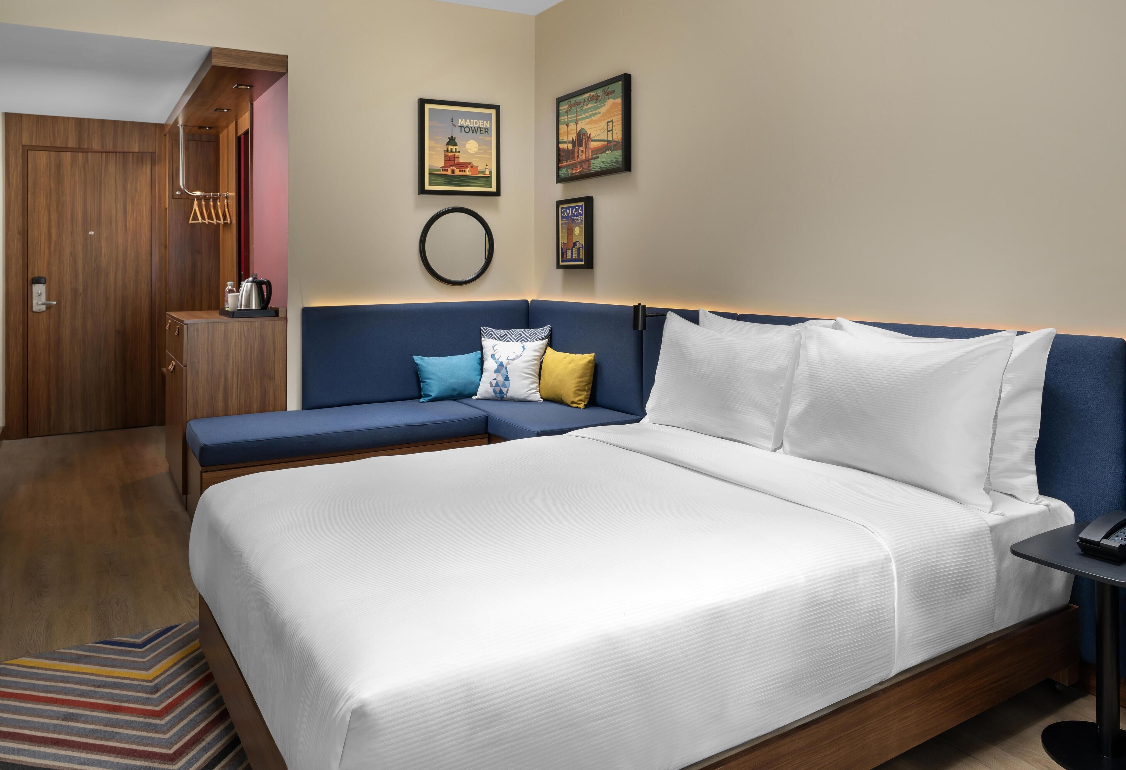 Ein modernes Hotelzimmer mit einem großen Bett, einer blauen Couch und einem Holzschrank.