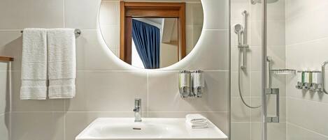 A bathroom with a white sink, a mirror, and a shower.