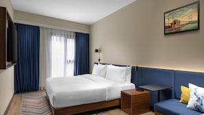 Ein modernes Hotelzimmer mit einem großen Bett, einer Couch, einem kleinen Tisch und einem Fernseher.