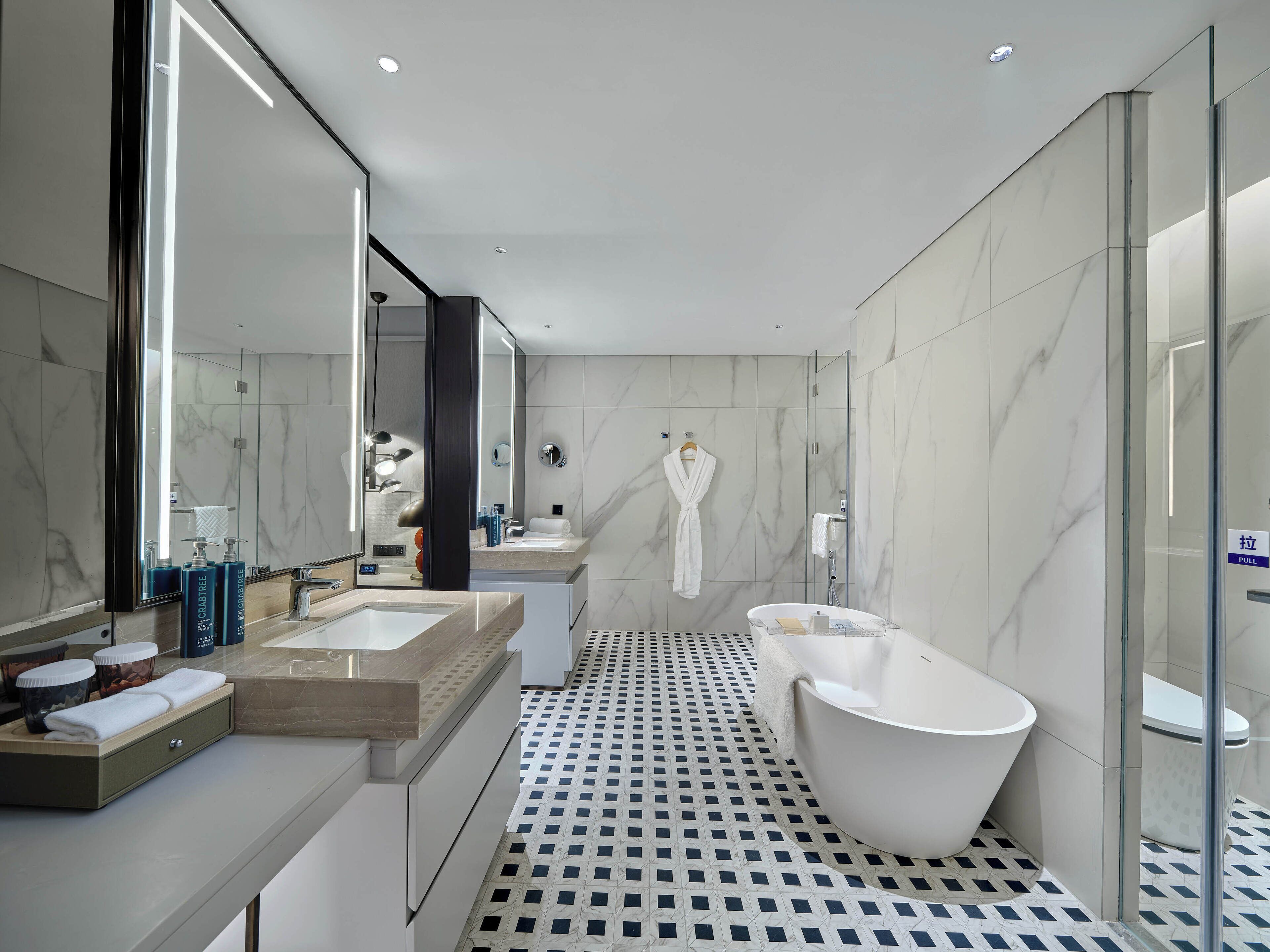 Un baño moderno con una bañera independiente, ducha con mampara de vidrio y tocador con un espejo grande.