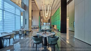 A modern hotel lobby with a central seating area, large windows, and a distinctive green wall. - Doubletree By Hilton Yanji (Yanbian)