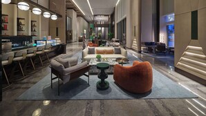 A spacious lobby with a modern design, featuring a seating area with sofas and chairs, a bar with a display, and a large window providing a view. - Doubletree By Hilton Yanji (Yanbian)