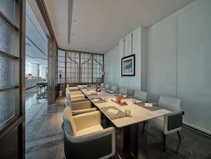 Meetings take place around a long, rectangular table in this conference room, surrounded by cushioned chairs and artwork.