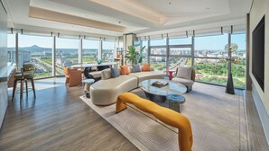A spacious living room with a large sofa, a coffee table, and a view of a cityscape through large windows. - Doubletree By Hilton Yanji (Yanbian)