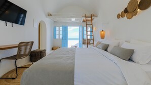 A bedroom with a bed, a chair, a TV, a ladder, and a view of the outside. - SunSea Living Suites (Santorini)