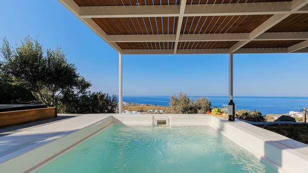 A pool area with a wooden ceiling and a view of the sea. - SunSea Living Suites (Santorini)