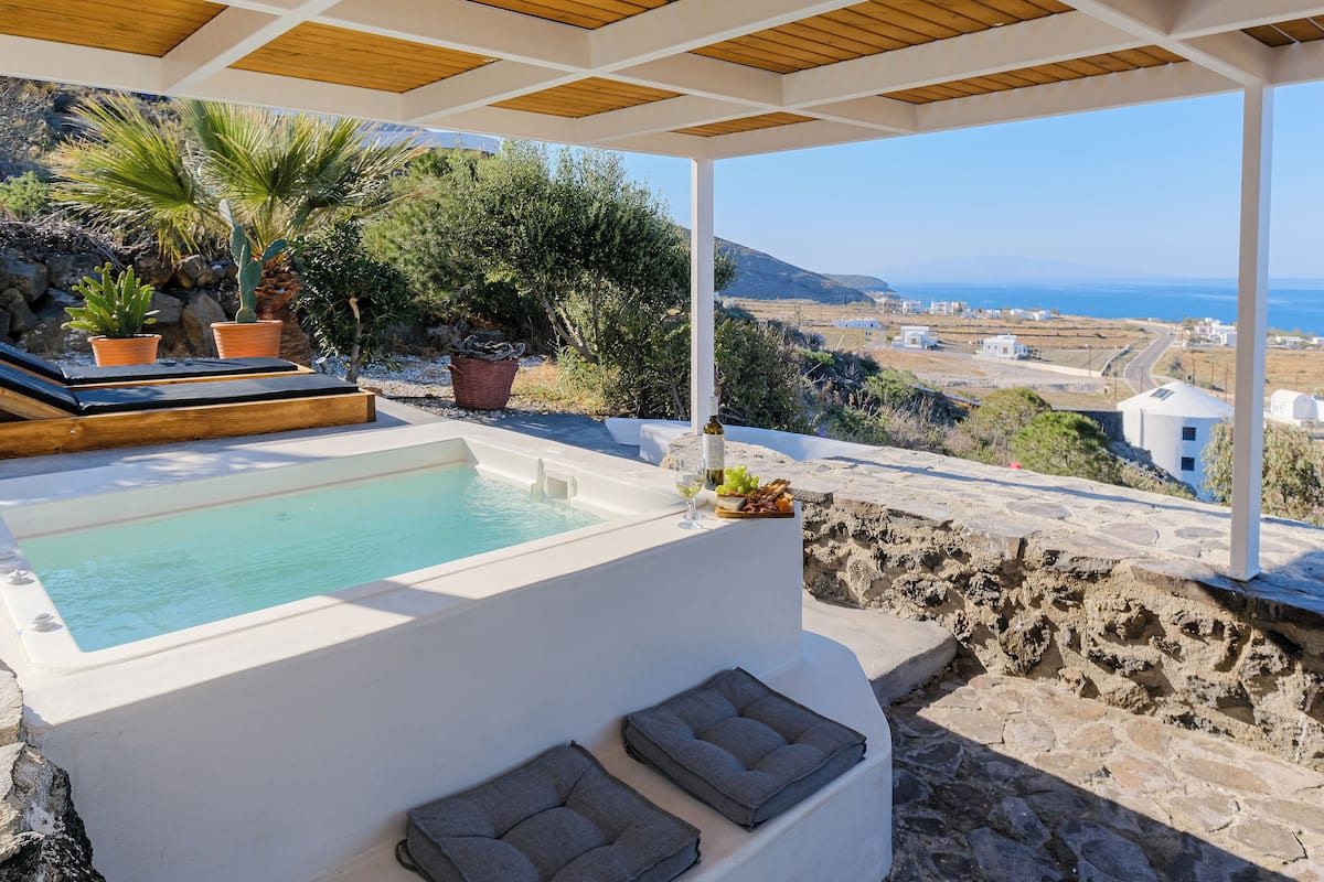 A pool area with a view of the sea and a white building.