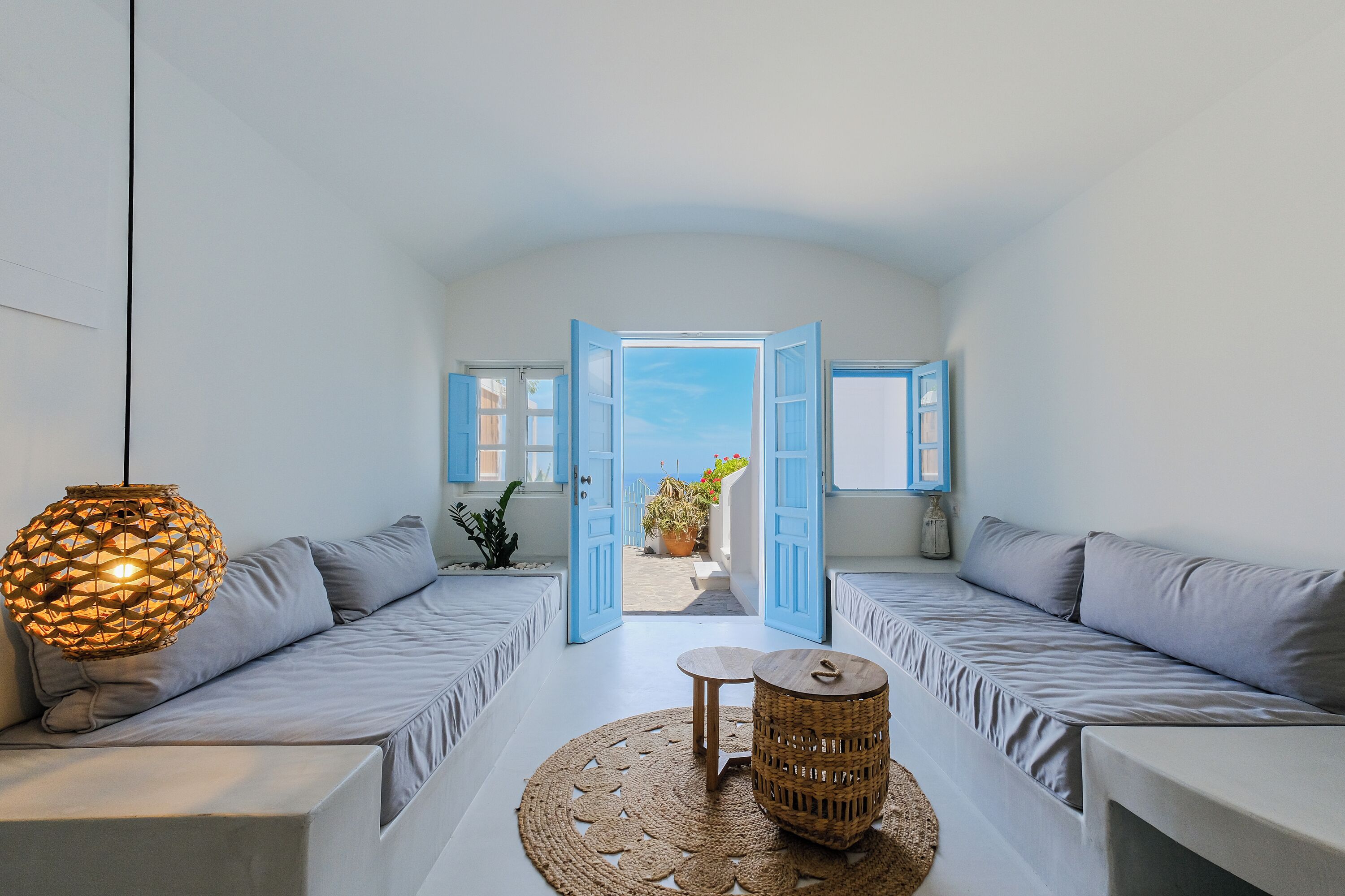 Una habitación moderna y minimalista con un conjunto de sofás, una mesita pequeña y una lámpara colgante.