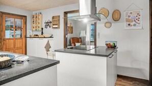 Une cuisine moderne dotée d’un îlot central, de meubles en bois et d’un coin repas avec une chaise.