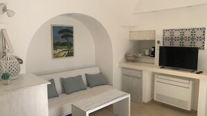A compact kitchen with a white countertop, a built-in oven, and a TV.
