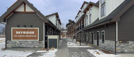 Una hilera de edificios modernos de varios pisos, con un letrero que indica 'SKYRIDGE 750 HARVIE HEIGHTS RD'.