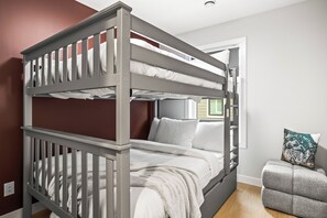 Ein Etagenbett mit weißer Bettwäsche und grauem Gestell in einem Zimmer mit roten Wänden und einem Fenster.