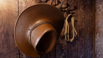 Un sombrero de cuero marrón colgado en una pared de madera con una cuerda.