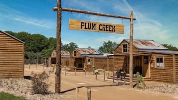 Een rustiek houten gebouw met een bord waarop 'PLUM CREEK' staat.