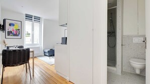 A modern apartment with a dining area, a living space, and a bathroom.